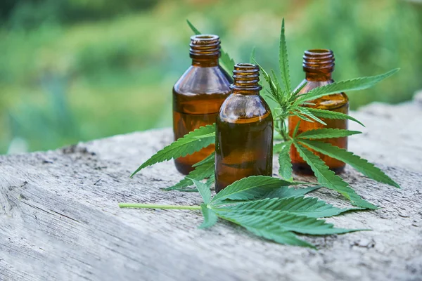Foglie di canapa su fondo di legno, semi, estratti di olio di cannabis in vasetti — Foto Stock