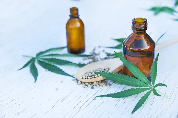 Hanfblätter auf Holzgrund, Samen, Cannabisöl-Extrakte in Gläsern — Stockfoto