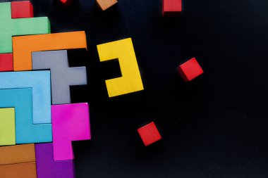 Farklı renkli ahşap bloklar siyah arka plan, düz yatıyordu üzerinde şekillendirir. Geometrik şekiller farklı renklerde, üstten görünüm. Yaratıcı, mantıksal düşünme veya problem çözme kavramı. Kopya alanı.