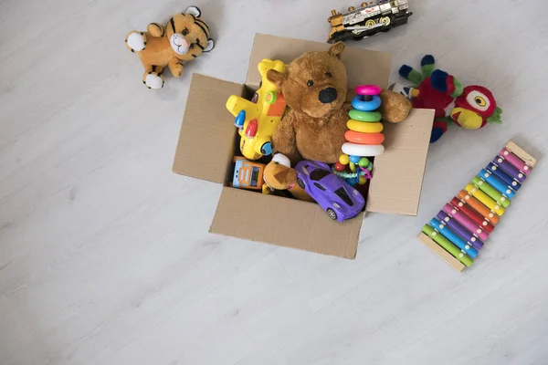 Коробка с игрушками на полу. Медвежонок в коробке, винтажный тон. благотворительный взнос. пожертвование. Благотворительность . — стоковое фото