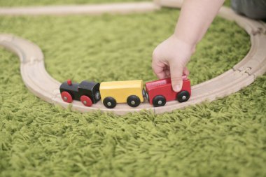 Küçük yürümeye başlayan bir kreş veya okul öncesi renkli çocuk odasında. Evde oyuncak göstergeleri ile oynayan çocuk çocuk. Asya bebek 2 yaşında yeşil bir halı üzerinde tek başına oynuyor.