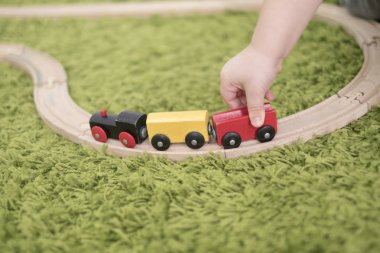 Küçük yürümeye başlayan bir kreş veya okul öncesi renkli çocuk odasında. Evde oyuncak göstergeleri ile oynayan çocuk çocuk. Asya bebek 2 yaşında yeşil bir halı üzerinde tek başına oynuyor.