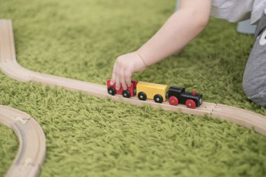 Küçük yürümeye başlayan bir kreş veya okul öncesi renkli çocuk odasında. Evde oyuncak göstergeleri ile oynayan çocuk çocuk. Asya bebek 2 yaşında yeşil bir halı üzerinde tek başına oynuyor.