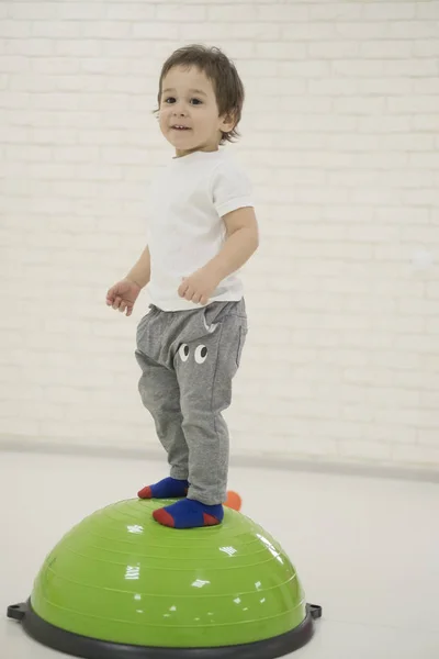 Happy child boy jumping on bouncing ball. — Stock Photo, Image