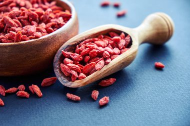 Goji kase ahşap masa üzerinde. Üstten görünüm kepçe ve kase taze Goji. Goji tablo üzerinde kalp şeklinde.