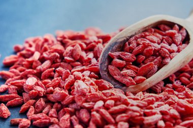 Goji kase ahşap masa üzerinde. Üstten görünüm kepçe ve kase taze Goji. Goji tablo üzerinde kalp şeklinde.