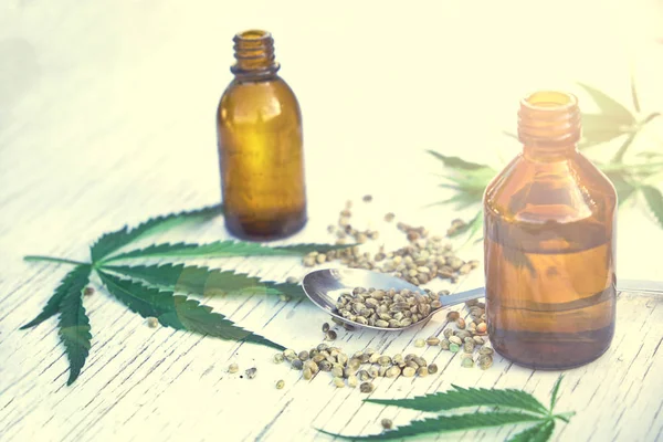 Hojas de cáñamo sobre fondo de madera, semillas, extractos de aceite de cannabis en frascos — Foto de Stock