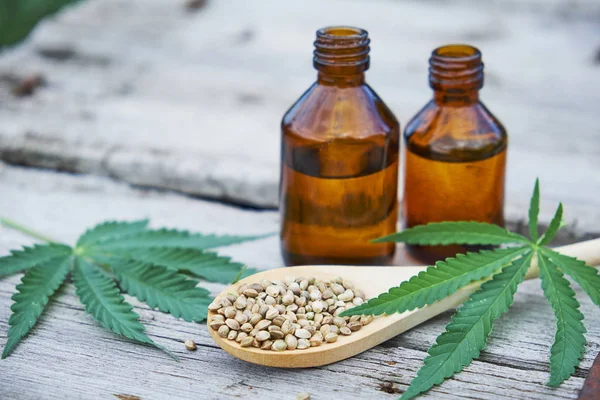 Hanfblätter auf Holzgrund, Samen, Cannabisöl-Extrakte in Gläsern — Stockfoto