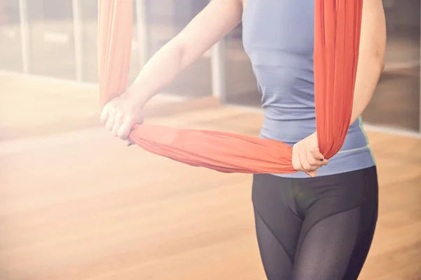 Adult woman practices aero anti-gravity yoga position in studio. Inversion bow pose in aero anti gravity yoga. Aerial exercises