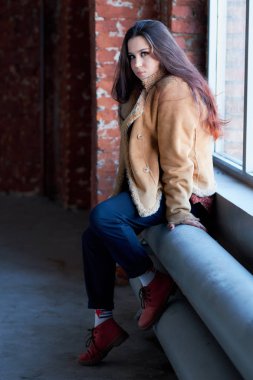 pencerenin yanında tek başına oturan üzgün kız. kış ceket, gençler için sokak modası.