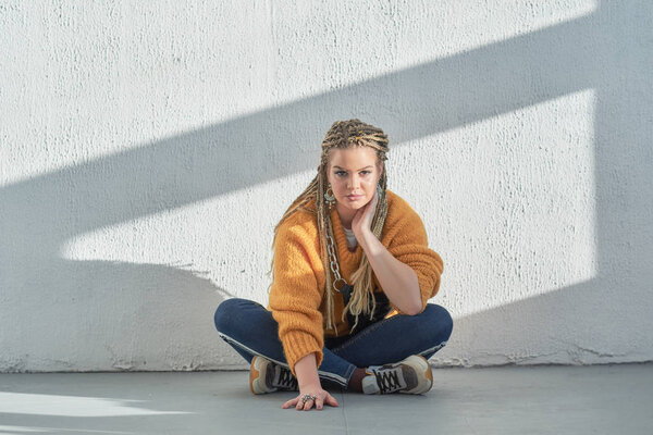 girl sits on the floor in a relaxed pose, an image of a modern teenager at school or college.