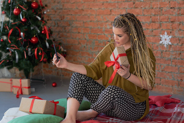 счастливая молодая красивая девушка разговаривает по телефону или делает селфи с ее подарком. Шоппинг на Рождество. использует смартфон, чтобы написать благодарственное сообщение за подарок
.