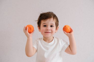 Sevimli çocuk mandalina tutar, beyaz üzerinde izole
