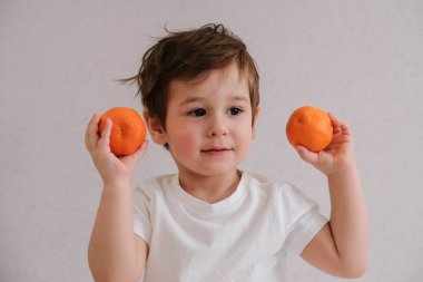 Sevimli çocuk mandalina tutar, beyaz üzerinde izole
