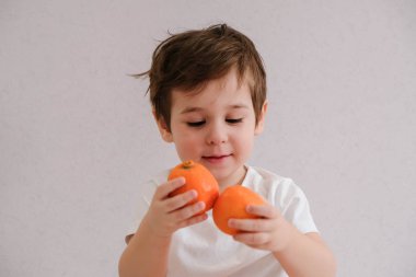 Sevimli çocuk mandalina tutar, beyaz üzerinde izole