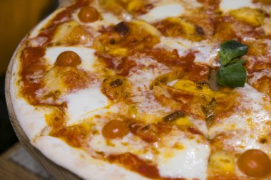 Gıda. Domatesli pizza, salam ve zeytin. Jambonlu, biberli ve zeytinli pizza. Ahşap masada servis edilen lezzetli taze pizza.