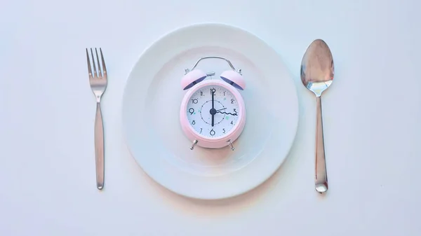 Ρολόι σε ένα άδειο πιάτο, λευκό φόντο. η έννοια του περιορισμού της πρόσληψης τροφής. — Φωτογραφία Αρχείου