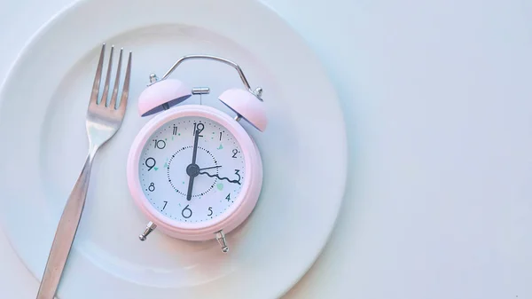 Zegar na tle pusty talerz, biały. koncepcja ograniczenia spożycia żywności. — Zdjęcie stockowe