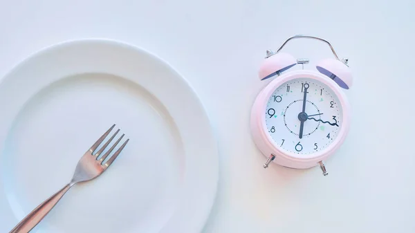 Relógio em um prato vazio, fundo branco. o conceito de limitação da ingestão de alimentos . — Fotografia de Stock