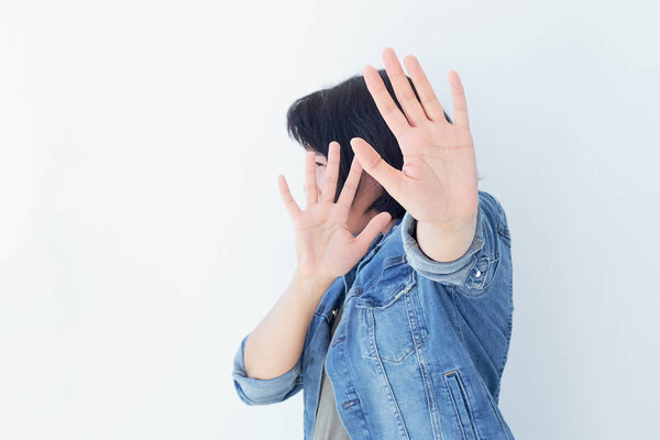 Young woman covering her face with palm saying no. Girl denying proposal, making stop gesture with her hand. Studio shot, copy space