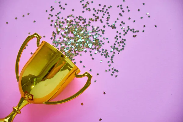Campeón trofeo copa de oro sobre fondo rosa. estilo minimalista, concepto de celebración de la victoria. y estrellas doradas de confeti se dispersan alrededor —  Fotos de Stock