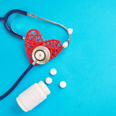 bir plastik kavanoz ve kalp şeklinde mavi bir arka planda bir stetoskop hapları. metin için boş alan.