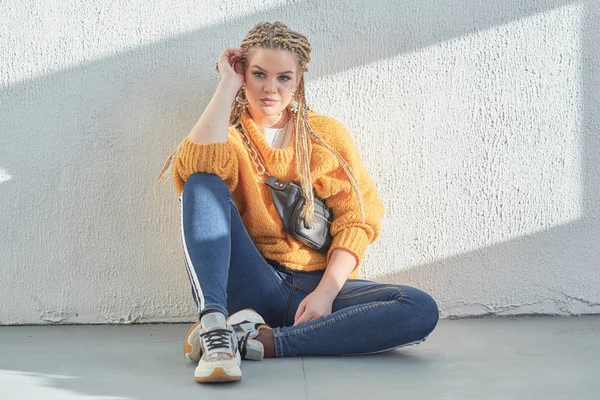 Chica se sienta en el suelo en una pose relajada, una imagen de un adolescente moderno en la escuela o la universidad . — Foto de Stock