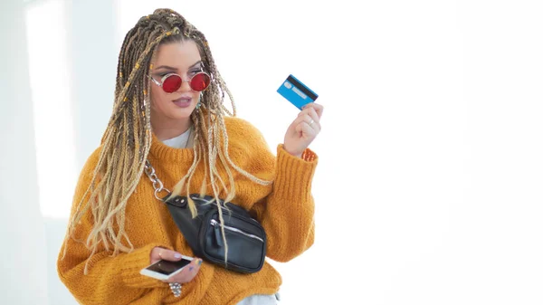 Stravagante plus size giovane donna con gli occhiali con uno smartphone e una carta di credito in mano . — Foto Stock