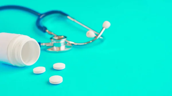 Aspirina y stetaskop sobre un fondo azul. pastillas blancas. cómo conseguir una droga — Foto de Stock