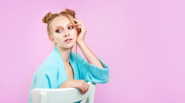 Genç güzel masum pembe bir arka plan üzerinde beyaz kadın portresi. Yüz kız giyim kış soğuk bez mutlu gülümseme. Güzellik tedavi mükemmel açık cilt makyaj yaşam tarzı kavramı afiş