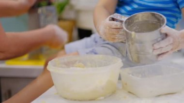 Mutlu gülümsedi büyükanne ve torunu bir hamuruna birlikte yoğurma yakın. Yaşlı bir kadın ve küçük çocuk yavaş hareket makarna veya pizza birlikte hazırlanıyor.