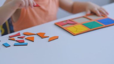 küçük Asyalı çocuk masada oturan bulmacalar toplar. Sevimli bir çocuk büyük çok renkli detaylardan bir resim toplar. yavaş hareket. Öğretmen oyun ile çocuk içinde Montessori sınıf