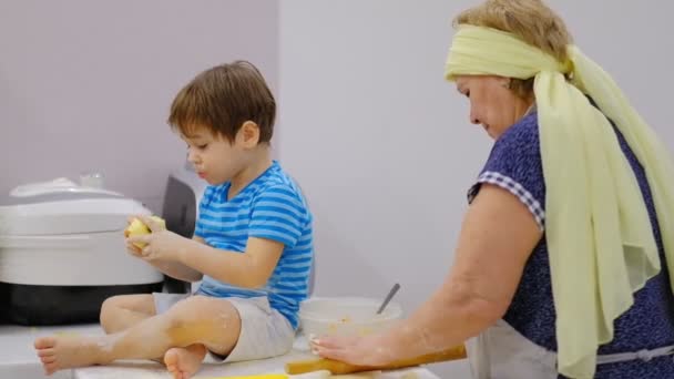 Primer plano de la feliz y sonriente abuela y nieto amasando un daugh juntos. cámara lenta de una anciana y un niño pequeño preparando pasta o pizza juntos . — Vídeos de Stock