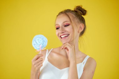 sarı parlak arka planda şeker ile genç kız. güzel makyaj,