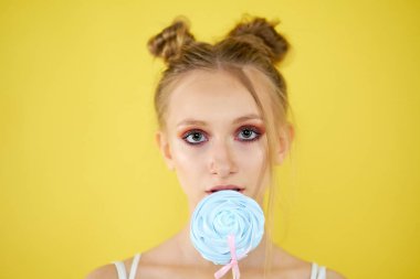sarı parlak arka planda şeker ile genç kız. güzel makyaj,