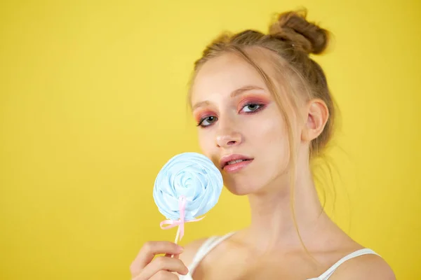 Fiatal lány cukorkát egy sárga fényes háttér. szép make-up, — Stock Fotó