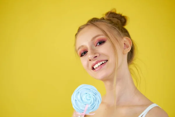 Chica joven con dulces sobre un fondo amarillo brillante. maquillaje hermoso , — Foto de Stock