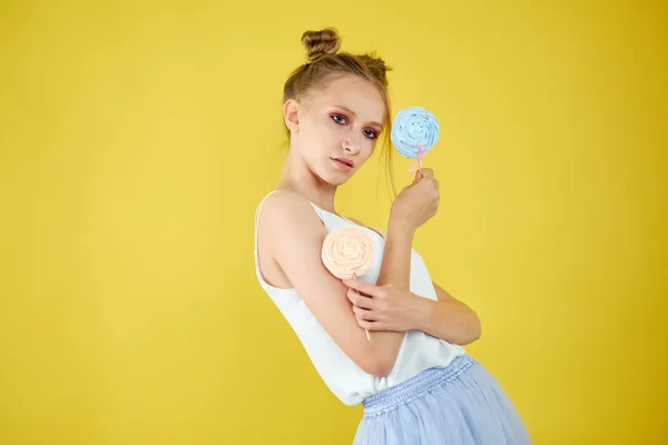 Młoda dziewczyna z cukierkami na żółtym jasnym tle. piękny makijaż, — Zdjęcie stockowe