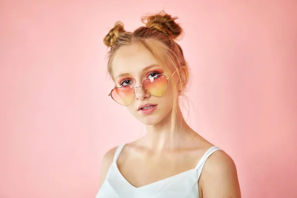 Портрет красивая молодая женщина в розовых солнцезащитных очках формы сердца. девушка со смешной прической на ярком фоне — стоковое фото
