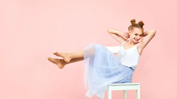 Mooie blonde meisje in het beeld van een prinses op een roze achtergrond is niet zittend stoel. studio portret — Stockfoto