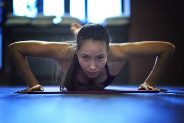 Kadın el push ups egzersiz bir spor salonunda sabah, güneş ışığı etkisi yaparak kapatın.