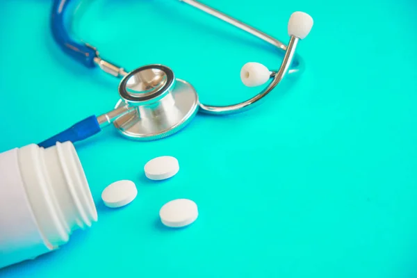 Aspirina y stetaskop sobre un fondo azul. pastillas blancas. cómo conseguir una droga — Foto de Stock