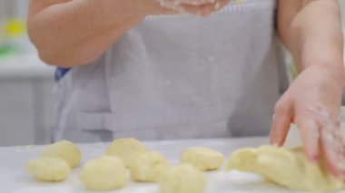 Mutlu gülümsedi büyükanne ve torunu bir hamuruna birlikte yoğurma yakın. Yaşlı bir kadın ve küçük çocuk yavaş hareket makarna veya pizza birlikte hazırlanıyor.