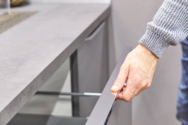 Mutfak dolap kapı açma kolu üzerinde el