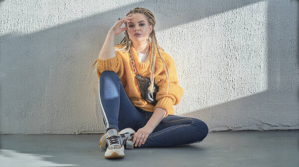 girl sits on the floor in a relaxed pose, an image of a modern teenager at school or college.