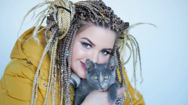 Portrét excentrické moderní mladé ženy, zářivý make-up a roztomilá kočička v dlaních. — Stock fotografie