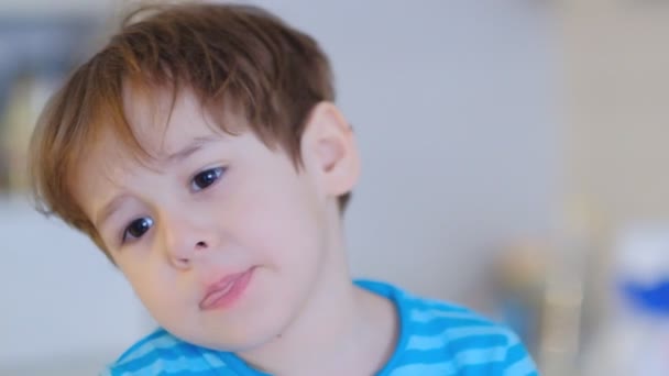 Niño cara triste de tres años, sentado en la cocina en casa y hablando en la cámara — Vídeo de stock
