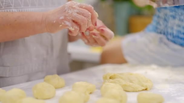 Grootmoeder en kleinzoon hebben samen plezier. een gelukkige familie. Senior vrouw en kleine jongen kneden deeg in meel op tafel — Stockvideo