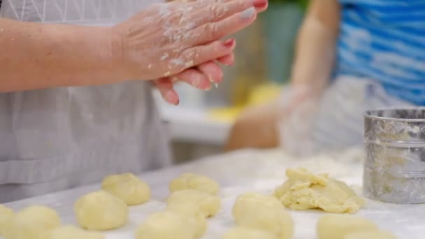 Babcia i wnuk bawią się razem. szczęśliwą rodziną. Starszy kobieta i mały chłopiec Kneading ciasto w mąka na tabela — Wideo stockowe