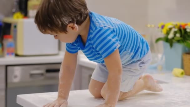 Grappige jongen spelen in de keuken met bloem. lastige kind op hom. ondeugende kinderen — Stockvideo